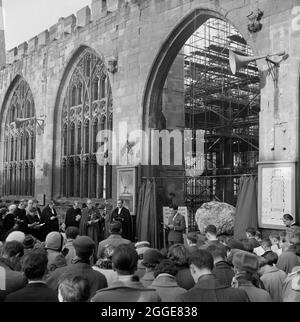 Une foule de personnes se sont rassemblées à l'extérieur de la cathédrale de Coventry pour le dévoilement du Boulder de Bethléem. Le rocher qui a été apporté d'une colline à Bethléem a été transporté à la cathédrale de Coventry pour être utilisé comme sa nouvelle police. Pesant trois tonnes, il a été transporté aux docks de Manchester dans le Prince Norman SS, puis à Coventry. La cérémonie de dévoilement a eu lieu le 22 décembre 1960 et le rocher a été dévoilé par Henry Sumner, âgé de 7 ans, fils du charpentier du contremaître à la cathédrale de Coventry. Le bloc a ensuite été déplacé à sa position actuelle devant la fenêtre du baptistère. Banque D'Images