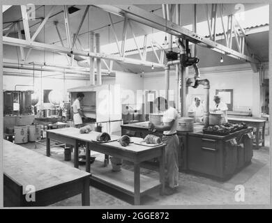 La cuisine du camp Balfour Beatty sur le site de construction de la centrale nucléaire de Berkeley avec quatre hommes qui cuisent et préparent la nourriture pour les travailleurs. Cette image a été cataloguée dans le cadre du projet Breaking New Ground en partenariat avec la John Laing Charitable Trust en 2019-20. Banque D'Images
