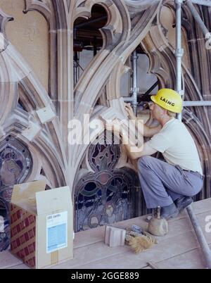 Une pierre de Laing travaillant sur la restauration de la fenêtre est à la cathédrale de Carlisle, en positionnant un nouveau morceau de pierre dans la trainerie à l'aide de la pâte Cerrtite SBD pour le coller au tissu existant. En 1961, N M Phillips, l'architecte de la cathédrale de Carlisle, a commencé à expérimenter le matériau de collage SBD Certite dans la restauration de la cathédrale. Il a été utilisé sur toutes les fenêtres gothiques décorées du Clerestory Sud et plus tard dans la restauration de la face nord de la cathédrale. En utilisant de la Cerrtite SBD, les grès Laing ont été capables d'enlever seulement la surface patientée de la pierre Banque D'Images