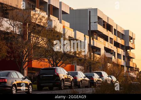 Bâtiments résidentiels modernes et voitures brillantes au coucher du soleil. Banque D'Images