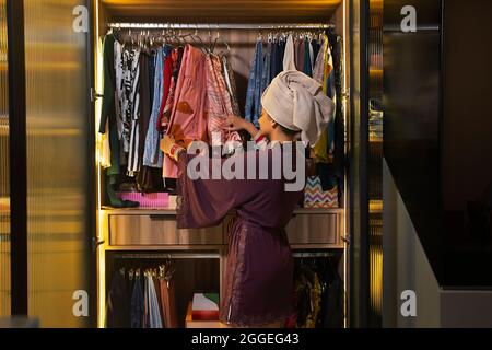 Une jeune femme nouvelle cueillir des vêtements dans son placard. Banque D'Images