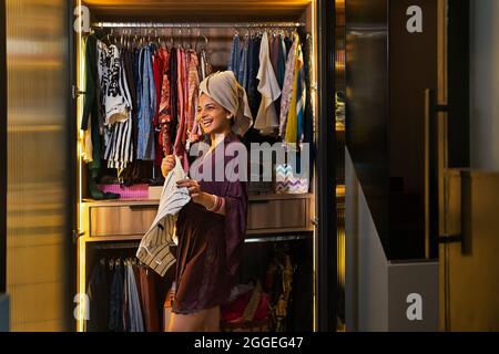 Une jeune femme récemment âgée se fait un plaisir de ramasser des vêtements dans son placard. Banque D'Images