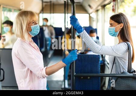 Quarantaine, pandémie de Covid. Portrait de profil de la vue latérale des femmes adultes et jeunes tenant des mains courantes dans les transports publics ou le métro portant des gants pour prot Banque D'Images