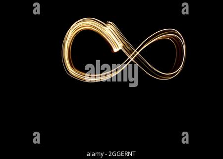 Tableau lumineux signe infini. Forme infinie dessinée avec des lumières dorées. Photographie en exposition prolongée. Banque D'Images