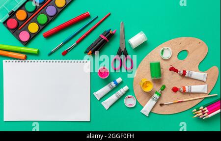 Enfants créatifs, peinture et dessin. Peintures et pinceaux colorés sur fond vert, papier vierge vide, espace de copie, modèle. Éducation, Back t Banque D'Images