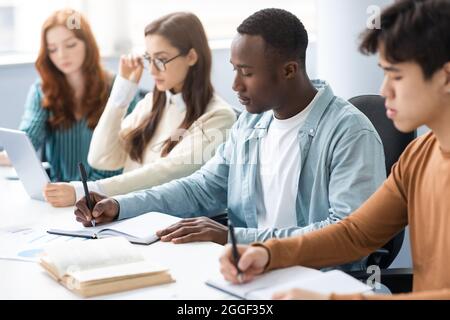 Concept du processus d'apprentissage. Portrait de divers élèves assis au bureau en ligne prenant des notes et travaillant ensemble sur Un projet de groupe. International vous Banque D'Images
