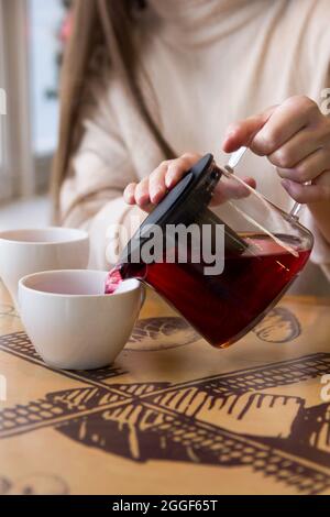 Versez le thé chaud dans une tasse. La tasse de thé sur la table en bois a été éclairée par la lumière douce du soleil qui a pénétré l'atmosphère chaude Banque D'Images