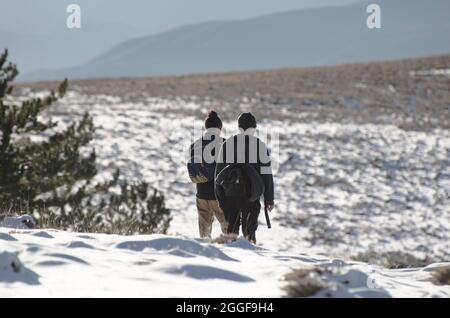 deux hommes avec sac à dos marchant dans un paysage de haute montagne enneigé, il est au-dessus des nuages Banque D'Images