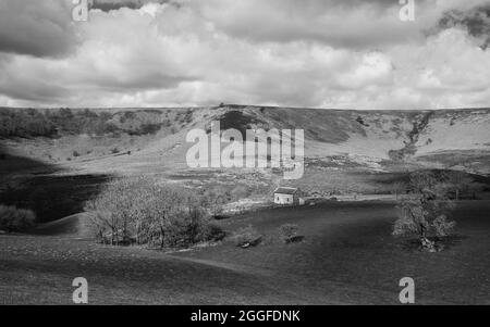 Dépression géologique naturelle avec un arbre de haut, un bâtiment abandonné et une lande sous le ciel avec des nuages à Hole of Horcum, Goathland, Royaume-Uni. Banque D'Images