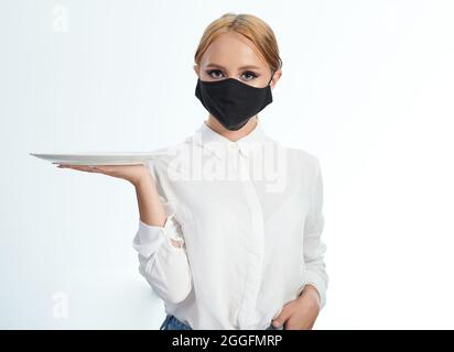 Jolie fille comme serveur dans le masque de visage isolé sur fond blanc de studio Banque D'Images