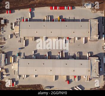 Les camions avec remorques attendent le chargement des marchandises pour le transport dans l'entrepôt de chargement. Vue aérienne de dessus tir de drone. Un grand terminal de transport de marchandises avec parking, camions et remorques. Banque D'Images