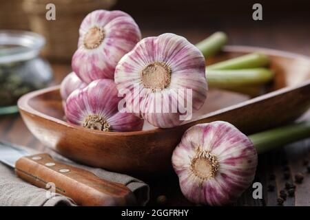 Plusieurs têtes d'ail de garlics dans un bol en bois sur une table de cuisine. Banque D'Images