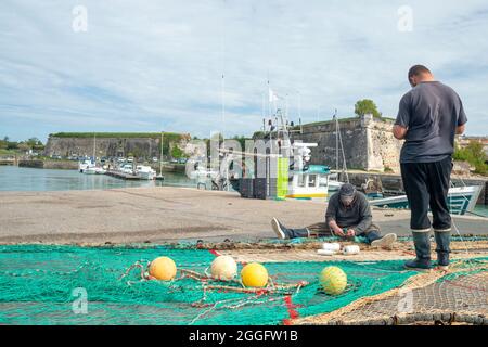 Île d'Oléron, Charente Maritime, France. 25th avril 2015 - pêcheurs qui font des filets de pêche au port de Château d'Oléron, France Banque D'Images