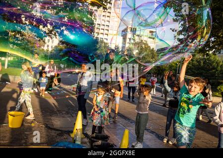 Les familles apprécient les divertissements de la rue le long de la Southbank à Londres tandis qu'un interprète souffle de grandes bulles à travers le pavé, Angleterre, Royaume-Uni. Banque D'Images