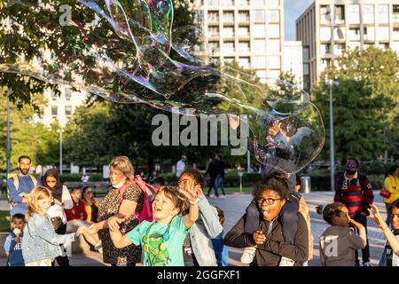 Les familles apprécient les divertissements de la rue le long de la Southbank à Londres tandis qu'un interprète souffle de grandes bulles à travers le pavé, Angleterre, Royaume-Uni. Banque D'Images