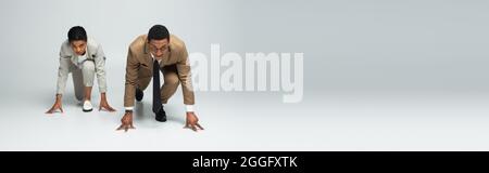 les hommes d'affaires afro-américains à commencer à poser avant de courir sur la bannière grise Banque D'Images