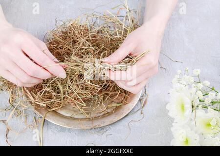 Comment faire un arrangement floral avec l'oeuf d'oie, le chrysanthème et le foin. Étape par étape, tutoriel. Banque D'Images