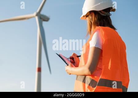 L'ingénieur de maintenance féminin contrôle le travail des éoliennes et des éoliennes. Technologie des énergies renouvelables. Production d'électricité verte. Banque D'Images