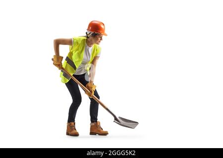 Femme travaillant avec un casque et une ceinture à outils, creusant avec une pelle isolée sur fond blanc Banque D'Images