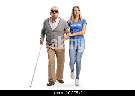 Portrait complet d'une jeune femme bénévole aidant un homme aveugle âgé marchant avec une canne isolée sur fond blanc Banque D'Images