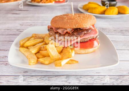 Hamburger classique avec deux viandes, jambon, banque, tomates en tranches et frites Banque D'Images