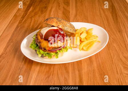 Hamburger de bœuf classique avec mayonnaise et ketchup, cornichons, oignons rouges crus, tranches de tomate, laitue et cheddar avec bacon frit. Pain au pavot Banque D'Images