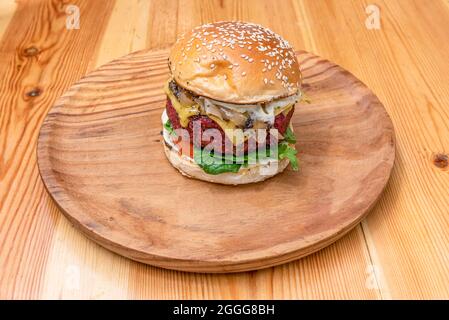 Hamburger avec filet de bœuf haché à la truffe, pousses d'épinards, mayonnaise à la tomate et à l'oignon et plus de mayonnaise au fromage fondu sur une assiette en bois Banque D'Images