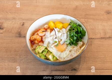 Bol de crevettes et œuf frit avec morceaux de noix de coco, coriandre, mangue hachée et avocats à base de riz blanc Banque D'Images