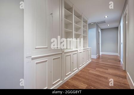 Bibliothèque en bois laqué sur mesure dans le couloir de la maison avec plancher en bois sombre Banque D'Images