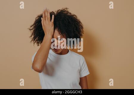 Femme fatiguée stressante à la peau foncée gardant la main sur le front souffrant de migraine de la tête Banque D'Images