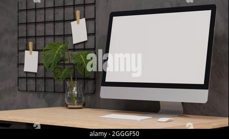Gros plan, ordinateur de bureau écran vide maquette sur table en bois avec feuille de monstera dans vase, tableau de note de grille sur mur gris dans le style moderne loft intérieur, Banque D'Images