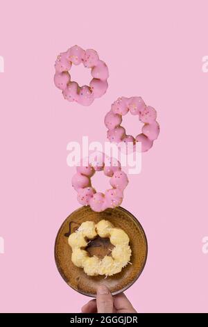 Beignets glacés avec un fond de couleur rose pâle. Concept alimentaire de lévitation. Banque D'Images