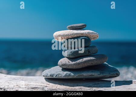 Pyramide de galets équilibrée sur la plage par une journée ensoleillée. Résumé bokeh de mer sur le fond. Mise au point sélective. Pierres Zen sur la plage de la mer, méditation Banque D'Images