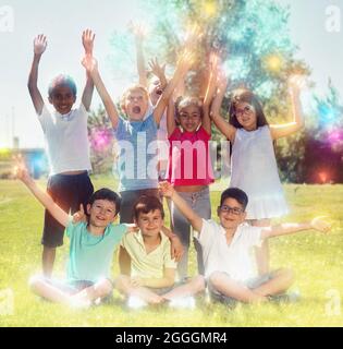 Des enfants heureux se tenant les mains et souriant ensemble dans le parc Banque D'Images
