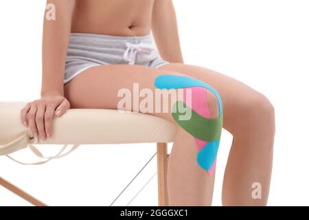 Genou femelle avec bande Physio kinesio, gros plan isolé sur fond blanc Banque D'Images