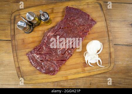 Vue de dessus d'une viande rouge fraîche juteuse avec des oignons tranchés sur le plateau en bois Banque D'Images