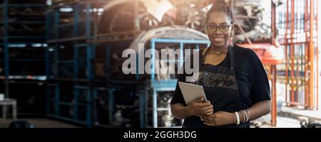 Portrait d'une femme afro-américaine noire tenant une tablette en usine de pièces de rechange pour automobiles anciennes Banque D'Images