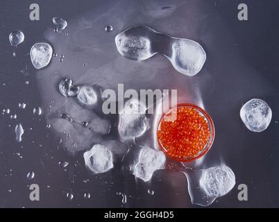 Œufs de saumon rouge avec glace sur fond en acier inoxydable Banque D'Images