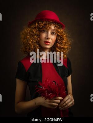 Portrait d'une belle femme avec une tenue rouge et noire nostalgique des années 1940 et une coiffure sur fond sombre. Photo de haute qualité Banque D'Images