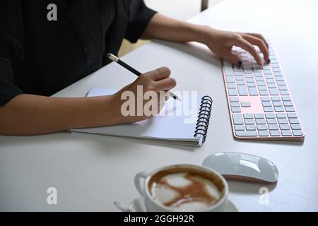 Femme d'affaires qui fait des notes sur le bloc-notes au bureau. Banque D'Images