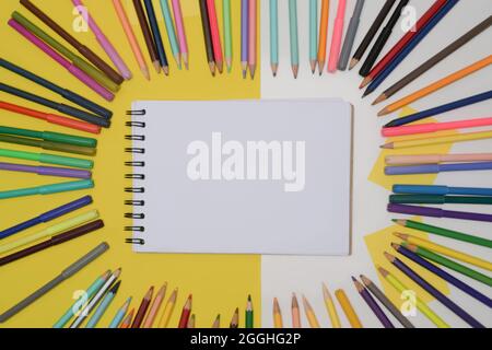 Vue de dessus Carnet d'esquisses vide entouré de crayons de couleur. Concept de retour à l'école. Banque D'Images