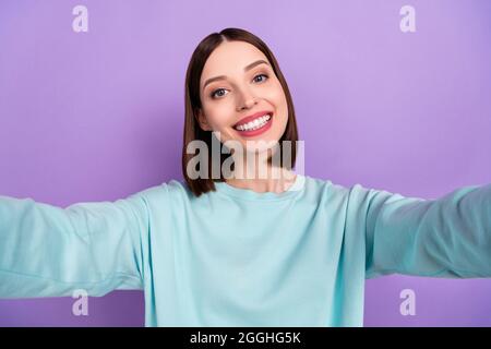 Photo portrait fille portant le pull bleu sourire heureux de prendre selfie isolé pastel violet couleur fond Banque D'Images