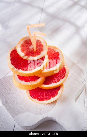 Apéritif avec tranches de pamplemousse rouge sur la bordure blanche Banque D'Images