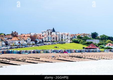 Vue le long de la plage de galets avec des groynes, et le quartier résidentiel de la ville. Des nuages noirs de pluie au-dessus de la ville, avec un ciel blanc et bleu au-dessus de la mer. Banque D'Images