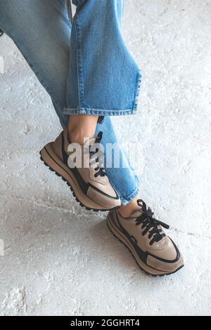 Femme en vêtements décontractés, jeans en denim bleu et baskets urbaines, photo de fond en béton Banque D'Images