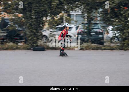 Ukraine, Kiev - 27 juin 2021: Entraînement de garçon pour patins en ligne. Patins en ligne à lames roulante, casque HQBC, protection contre les lames de puissance. Éditorial Banque D'Images