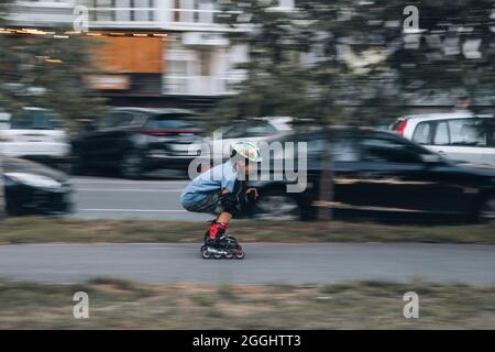 Ukraine, Kiev - 27 juin 2021: Entraînement de garçon pour patins en ligne. Patins en ligne à lames roulante, Author Helmet, Powerslide protection. Éditorial Banque D'Images