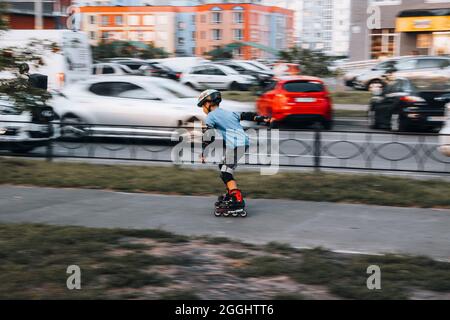 Ukraine, Kiev - 27 juin 2021: Entraînement de garçon pour patins en ligne. Patins en ligne à lames roulante, Author Helmet, Powerslide protection. Éditorial Banque D'Images