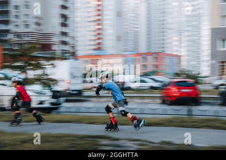 Ukraine, Kiev - 27 juin 2021: Entraînement de garçon pour patins en ligne. Patins en ligne à lames roulante, Author Helmet, Powerslide protection. Éditorial Banque D'Images