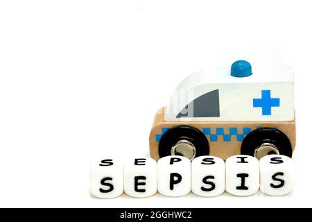 Un mot sepsis et une ambulance en bois de jouet , isolée sur fond blanc, un concept de conscience d'infection grave Banque D'Images